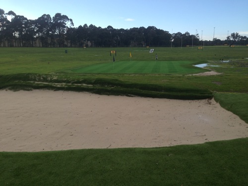 Chipping grass in the foreground and then the bunker and green